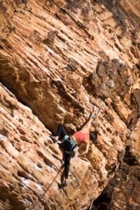 A woman climbing on a big rock.