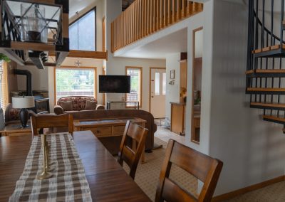 A cozy living room in this vacation home features patterned seating, a fireplace, a flat-screen TV, and large windows with stunning mountain views.