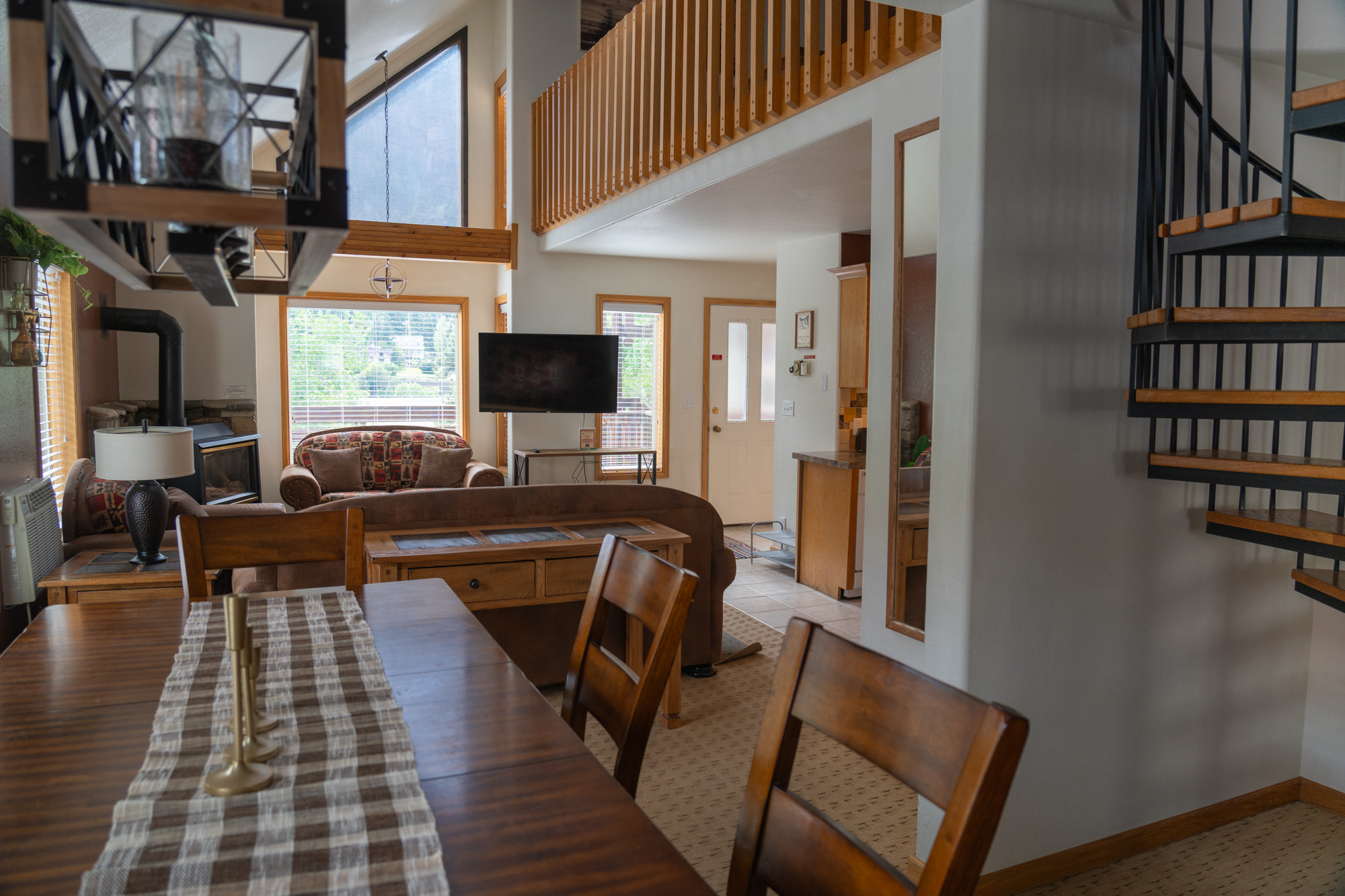 A cozy living room in this vacation home features patterned seating, a fireplace, a flat-screen TV, and large windows with stunning mountain views.