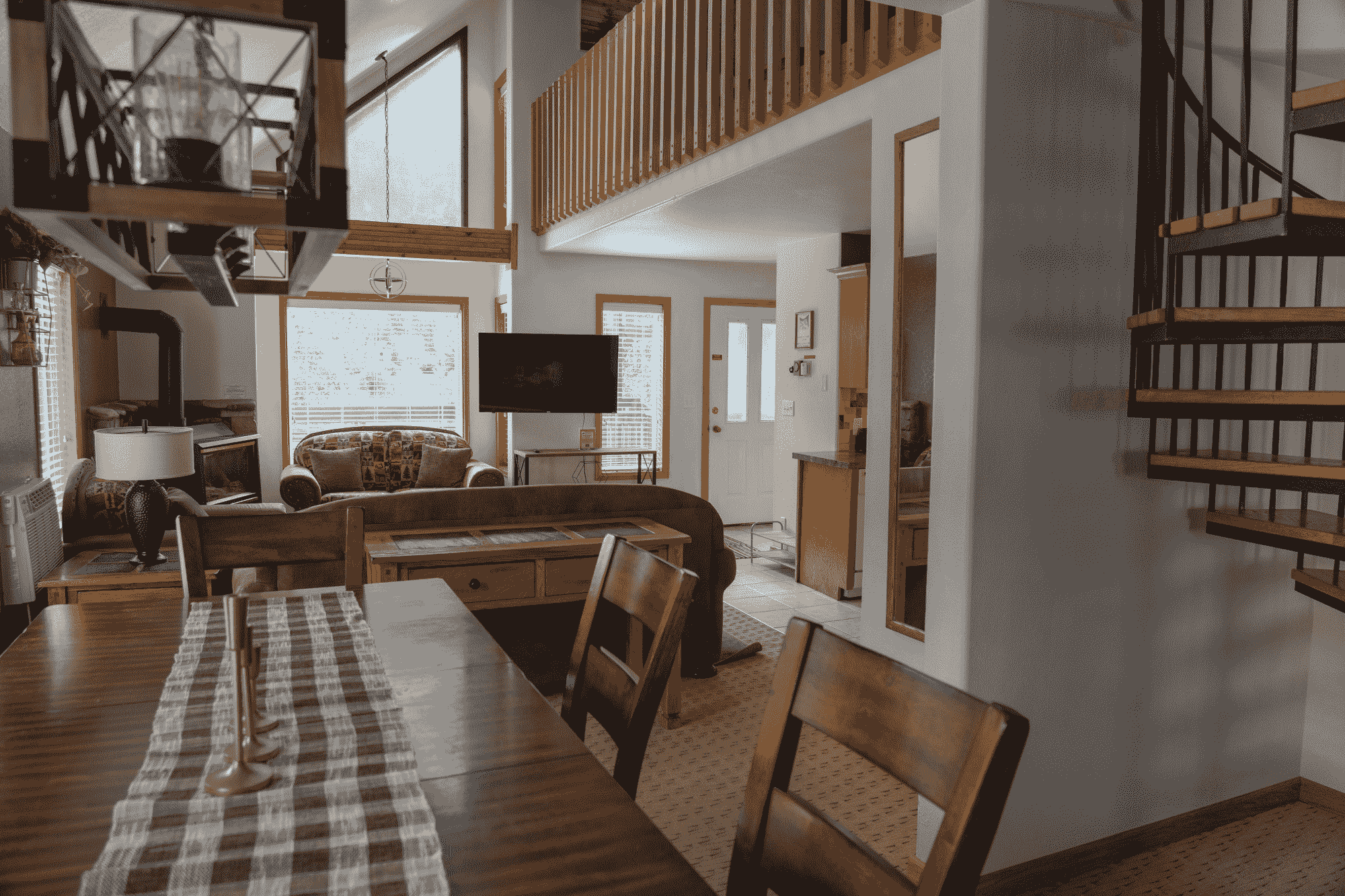 Cozy cabin interior with wooden furniture and spiral staircase.