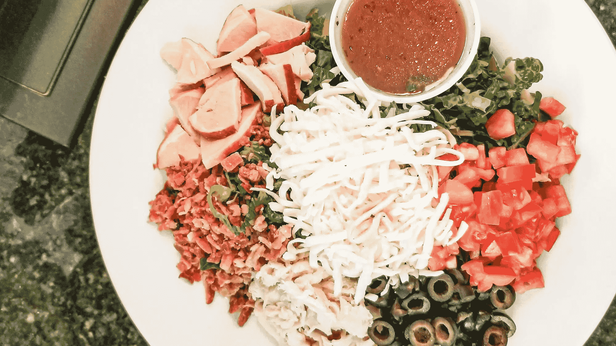 Fresh chopped salad with turkey, bacon, cheese, tomatoes, and olives.