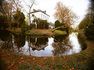 Old house by a tree-lined canal in autumn